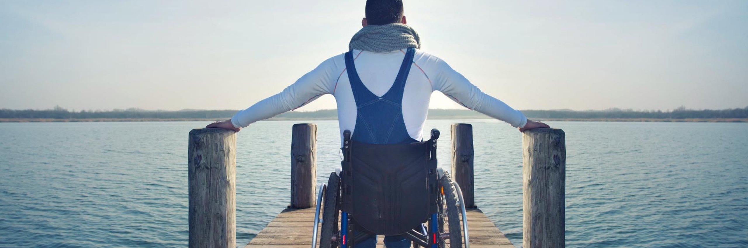 BRW | Privatlösung | Vorsorge | Mann im Rollstuhl ist am Steg und schaut ins Gewässer