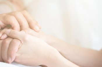 BRW | Privatlösung | Krankheit & Pflege | Pflegerin hält die Hand eines kranken Mannes